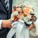 person holding orange and white flower arrangement