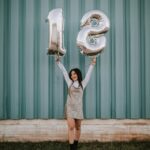 woman holding 1 and 8 balloons