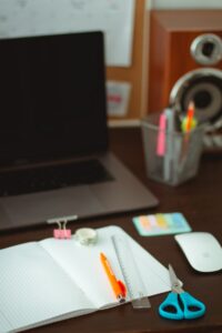 black and silver laptop computer beside white printer paper on brown wooden table